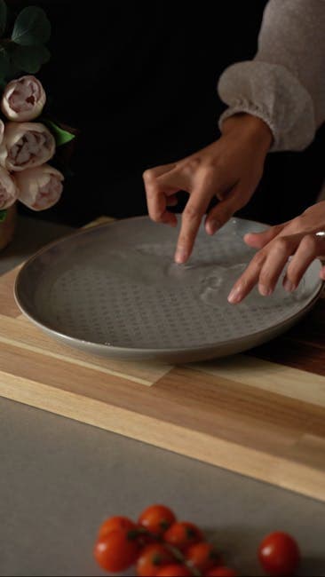 Close-up of hands preparing rice paper over a ceramic plate, ideal for Vietnamese cuisine concepts.
