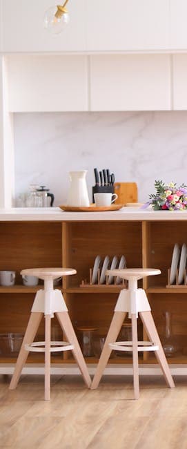 Elegant kitchen interior featuring wooden stools and organized shelves, perfect for contemporary home design.