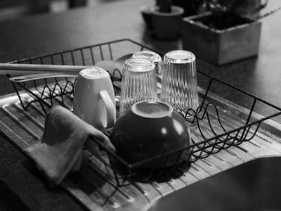 Black and white shot of a dish rack with glass and ceramic kitchenware.