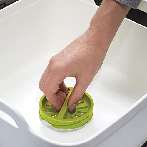Main utilisant un égouttoir plastique vert dans évier blanc
